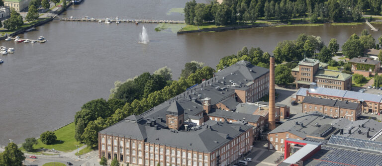 Ilmakuva Kokemäenjoen rannasta, etualalla Porin entinen puuvillatehdas.